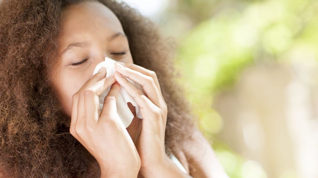 Teenage girl sneezing.