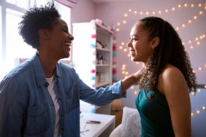 Mother Helping Teenage Daughter In Bedroom At Home Getting Ready For Prom Or Night Out