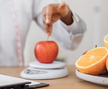 Specialist putting fruit on weighing instrument in office