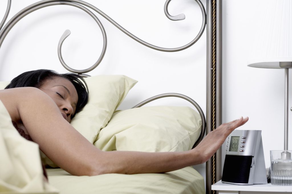 Woman in bed reaching for alarm radio