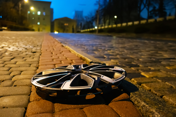 Car hubcap lies on the side of the road. Lost hubcap that fell off the car wheel